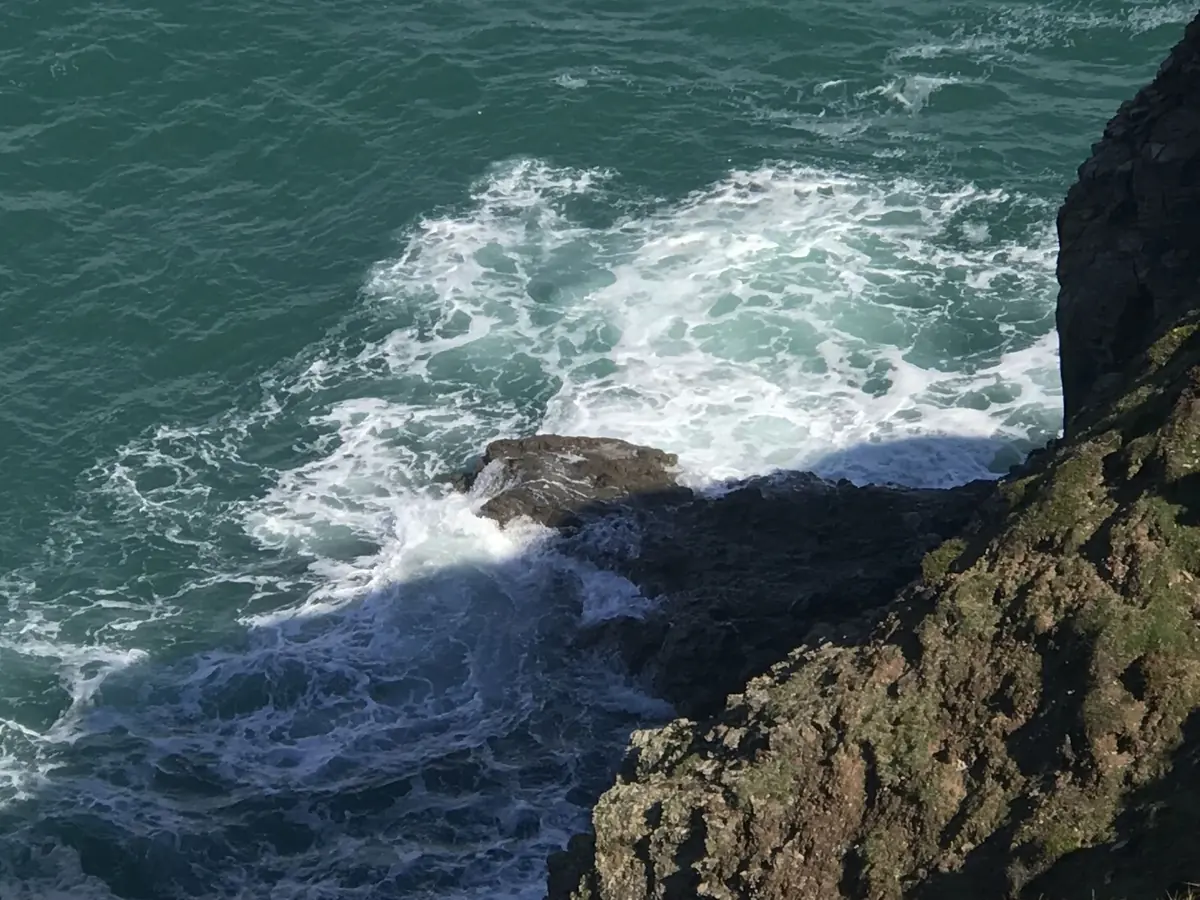 White surf swirling around a rock, seen from the clifftop