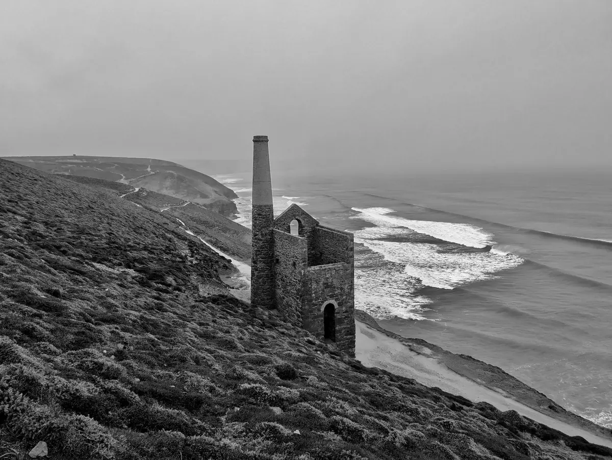 Black and white long exposure of an engine house above smooth surf